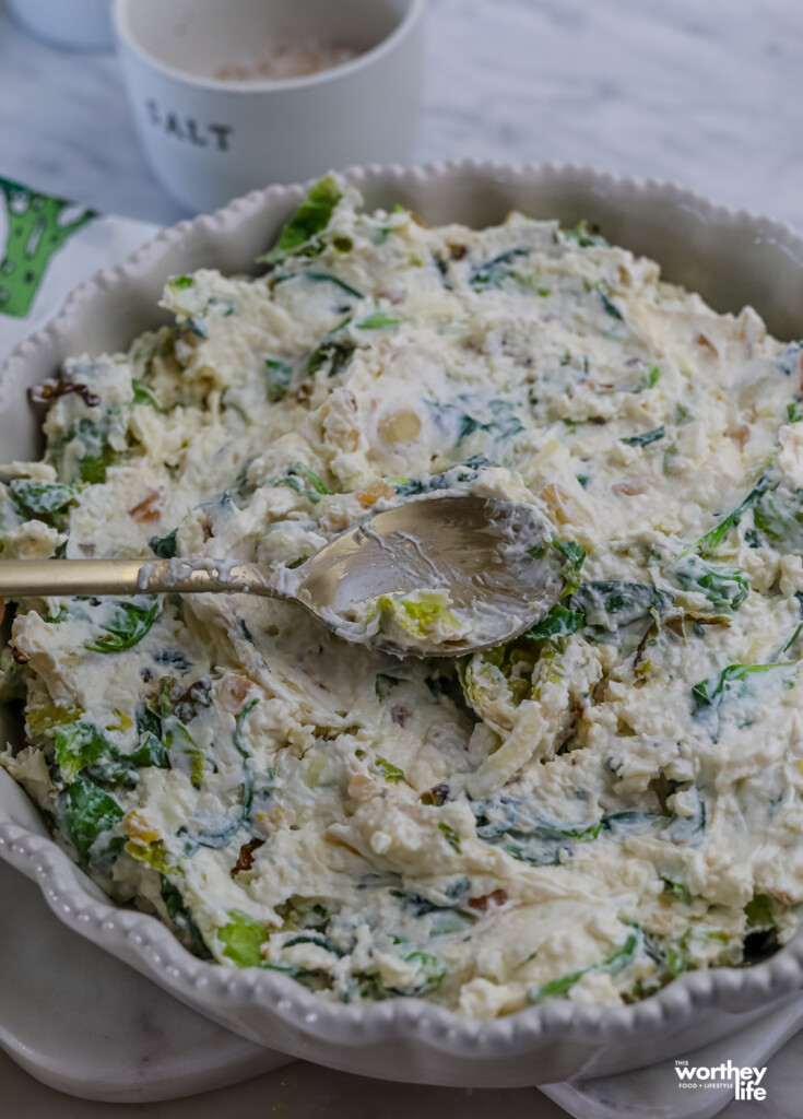 a brussels sprouts spinach dip in white pie pan ready to go in the oven