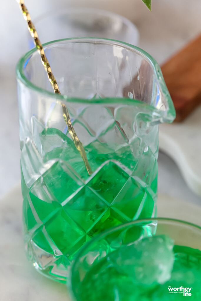 making a green mocktail in a cocktail mixing glass
