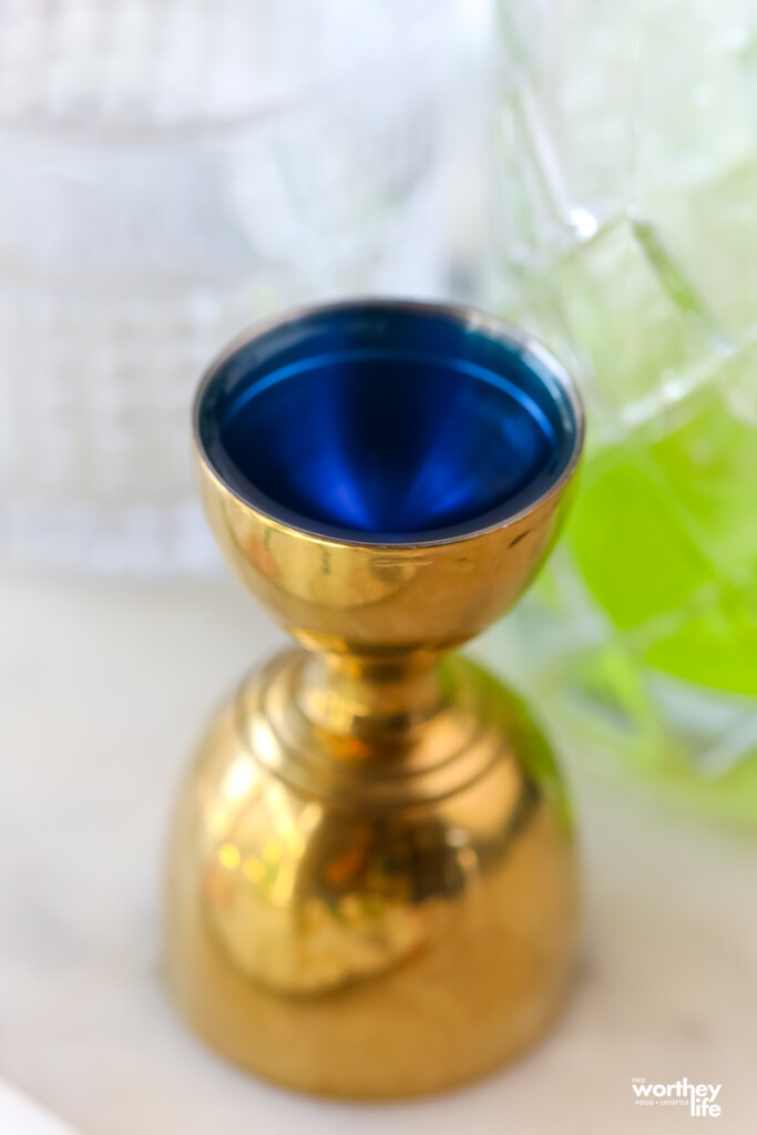 blue alcohol in a gold jigger