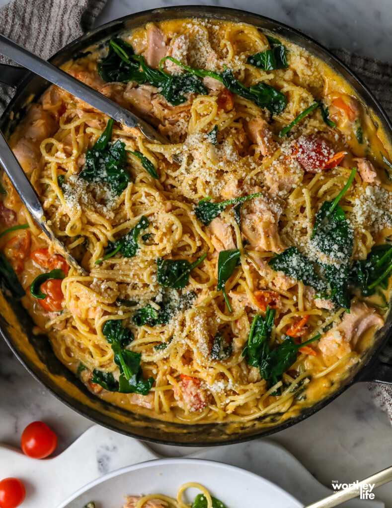 pasta in a skillet with salmon and spinach