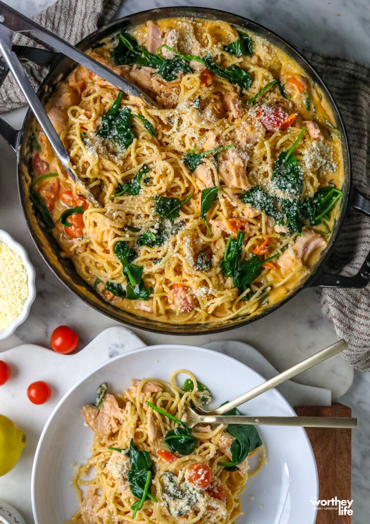 Pasta With Salmon and Spinach in a pan and a portion of it on a white plate
