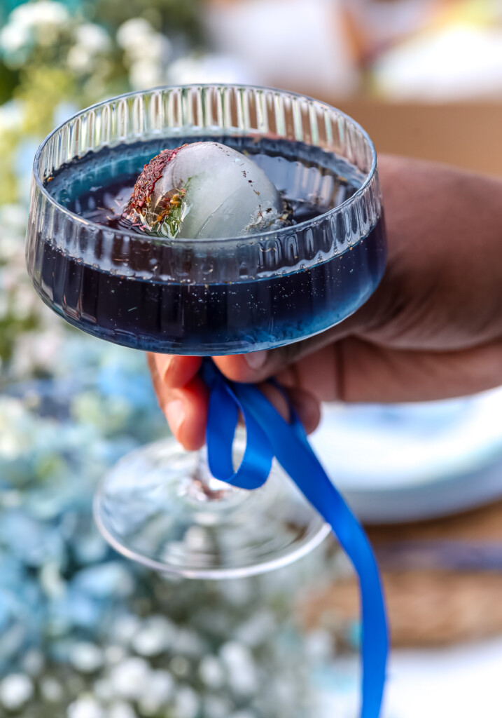 woman holding a blue mocktail with a blue ribbon