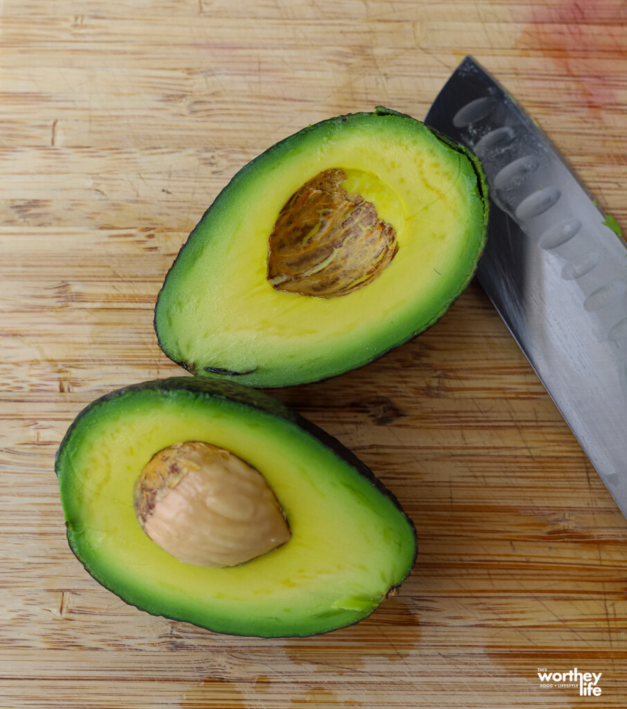 ripe avocado open in two on a cutting board