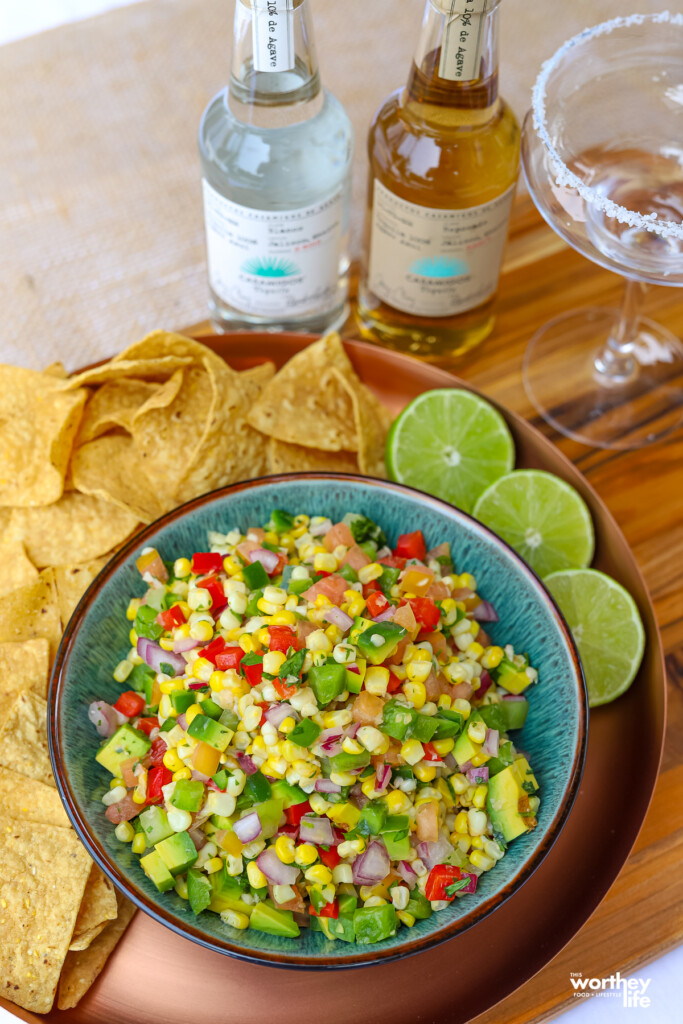 corn pico de gallo on a plate with fresh limes and tequila