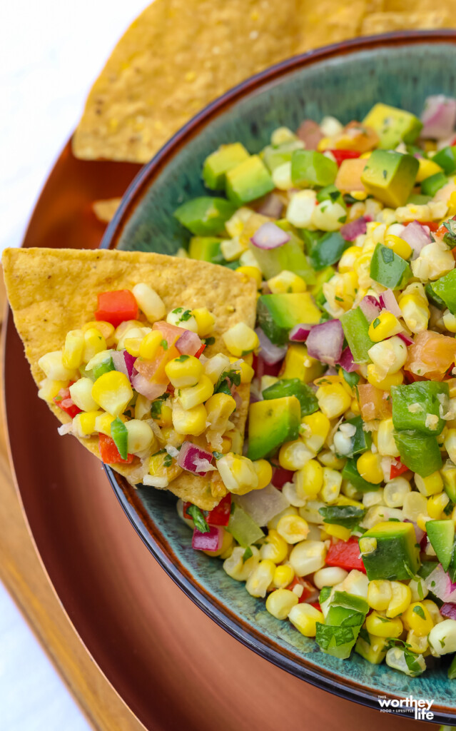 a piece of tortilla chip with corn pico de gallo salsa