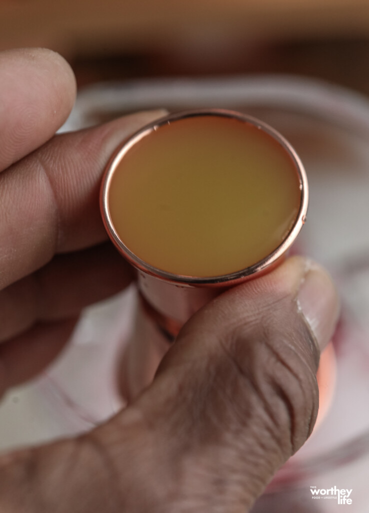 a man holding a jigger full of orange juice