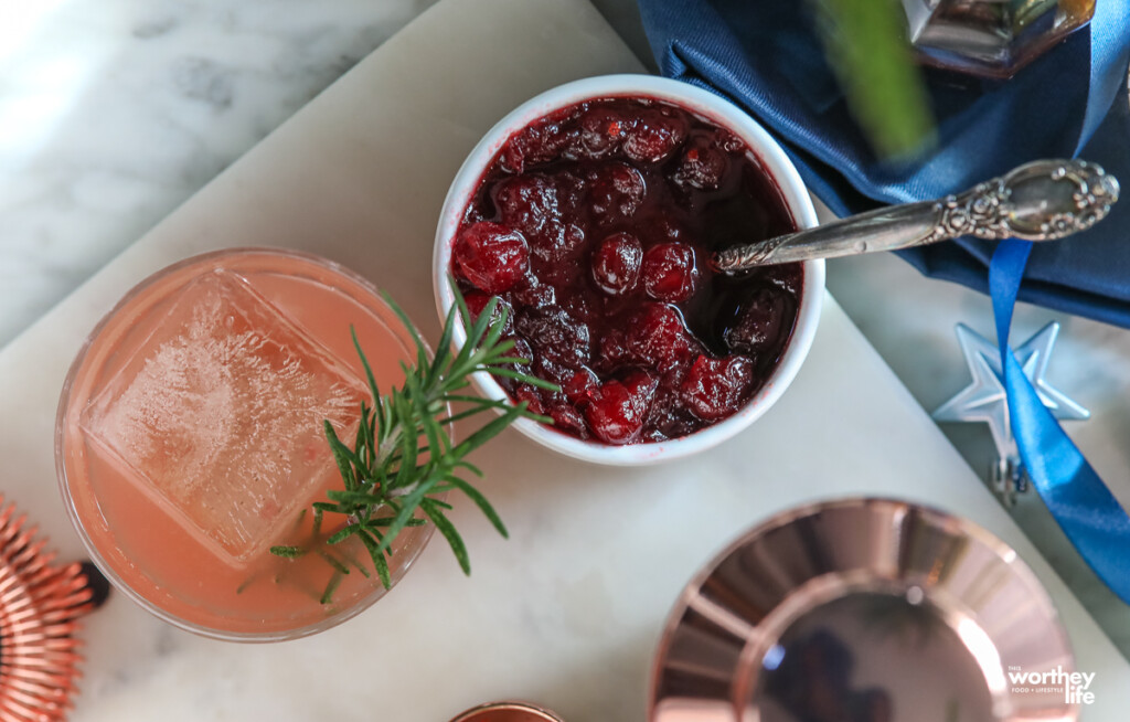 cranberry sauce in a white dish with a cranberry cocktail on a white marble background