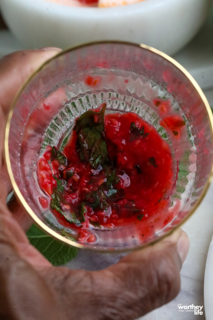 muddling raspberries in a glass